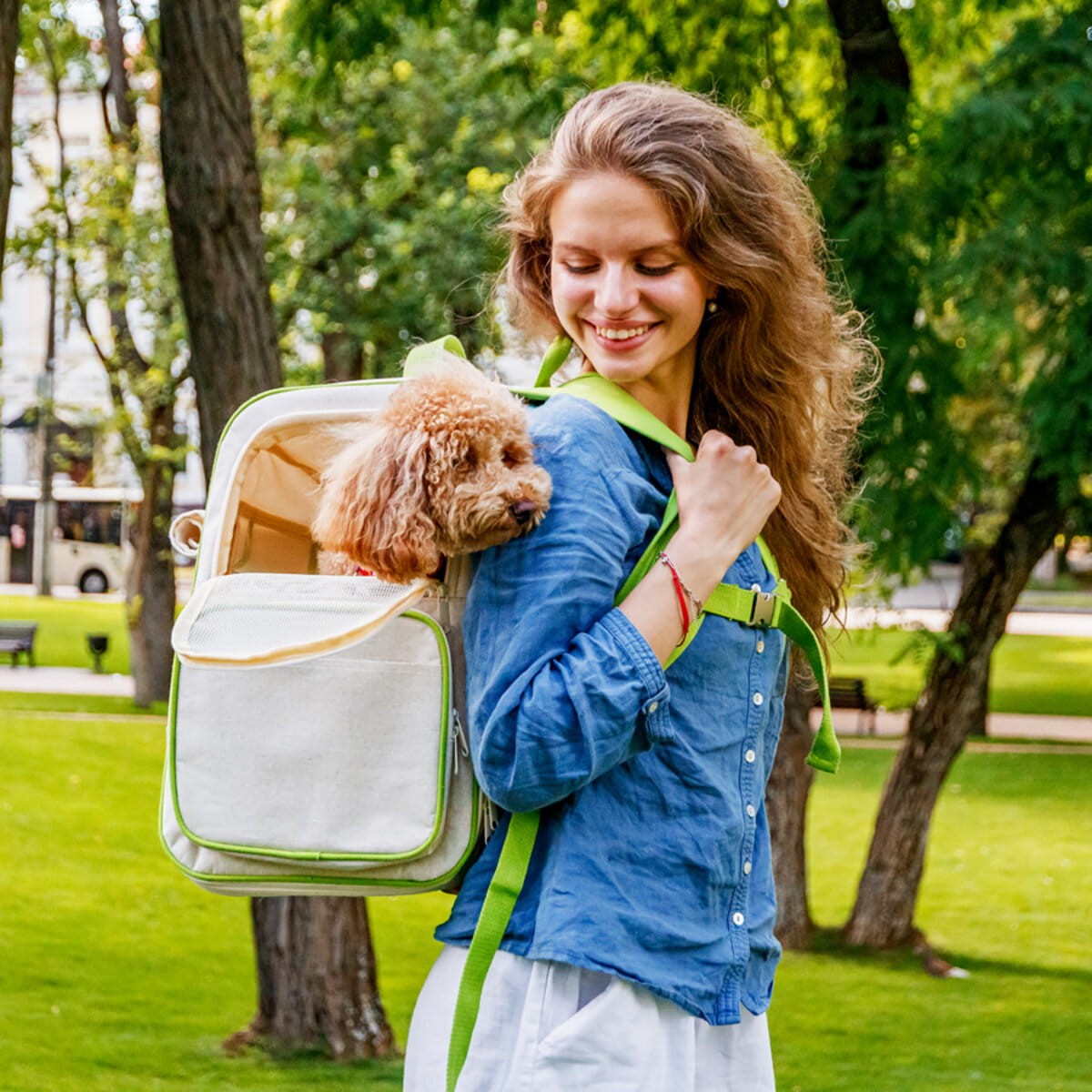Dziewczyna w parku niesie plecak  z pieskiem